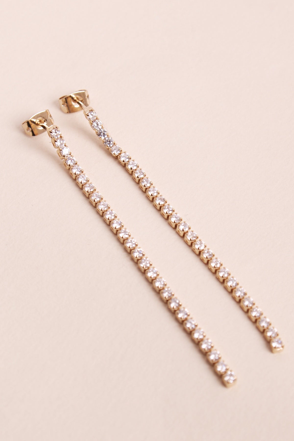 Paire de boucles d'oreilles en or et pierres de zirconium, pendante le long du cou.