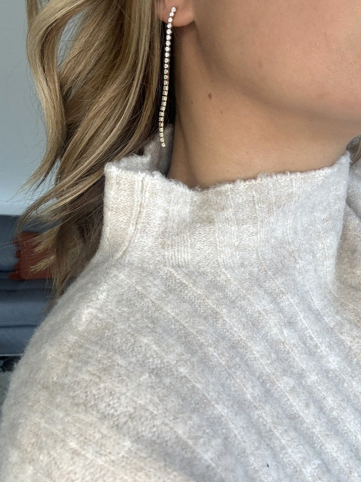Paire de boucles d'oreilles en or et pierres de zirconium, pendante le long du cou.